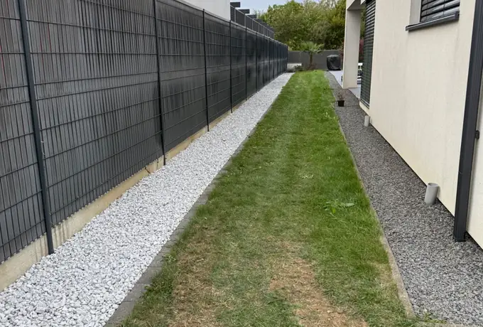 Bande de gazon fraîchement tondue et gravier décoratif le long d'une maison