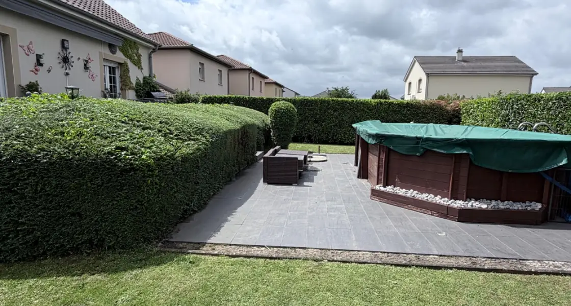 Jardin entretenu avec terrasse dallée, spa et haies taillées dans le nord mosellan