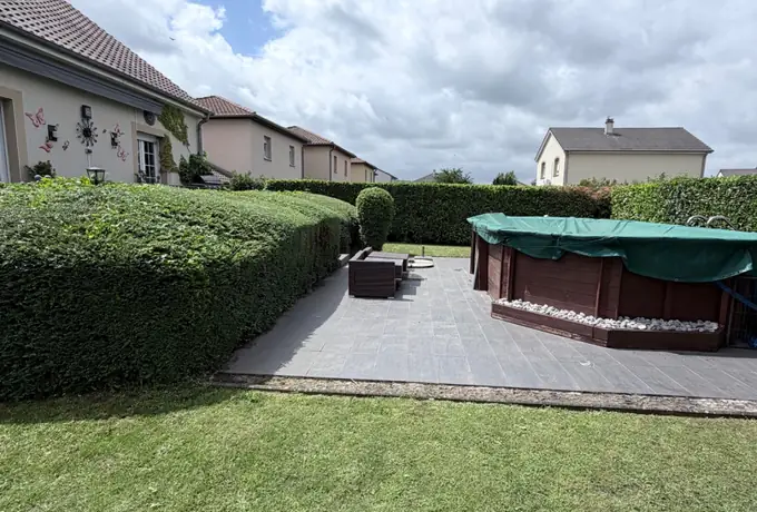 Jardin entretenu avec terrasse dallée, spa et haies taillées dans le nord mosellan