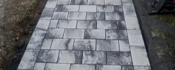 Allée pavée en damier gris et anthracite menant à une entrée de maison