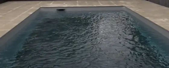 Piscine enterrée entourée d'une terrasse en dalles de pierre naturelle claire